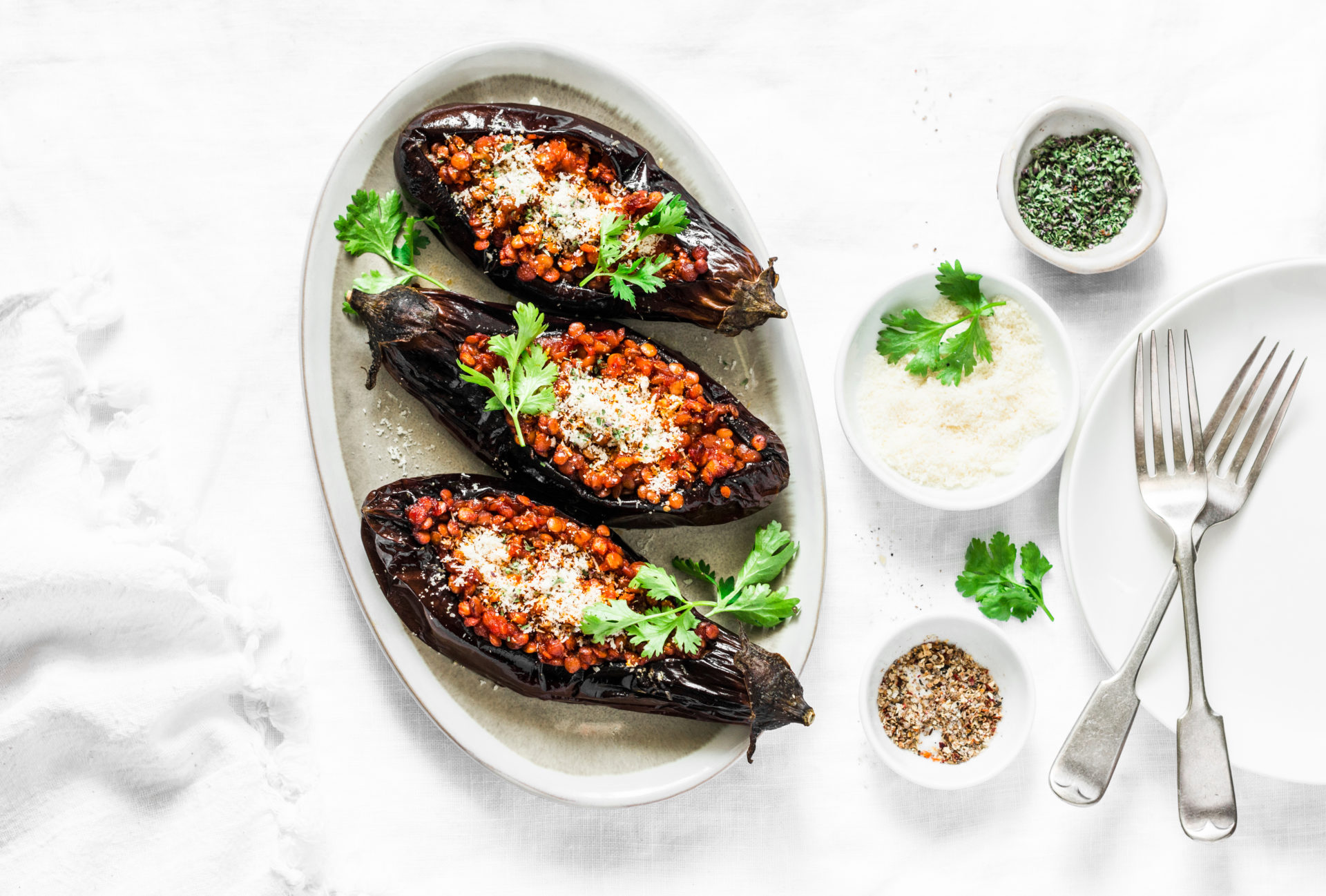 Stuffed lentils roasted eggplant - delicious healthy vegetarian served lunch  table. On a light background, top view