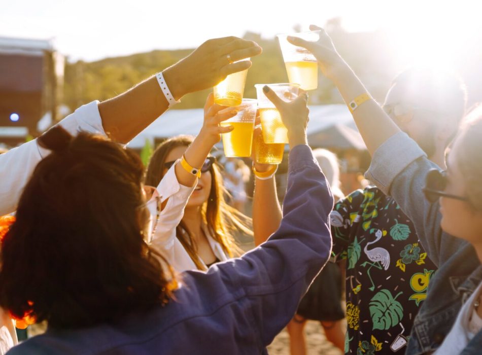 Young happy friends drinking beer and having fun at music festival together. Friendship.