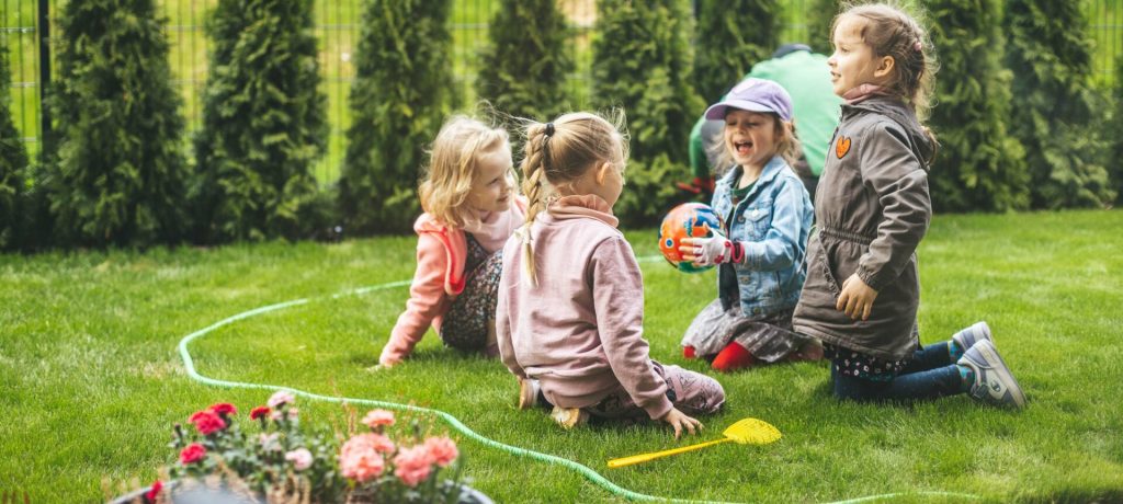 children-play-on-lawn-near-evergreen-trees-2026-03-18-13-46-48-utc