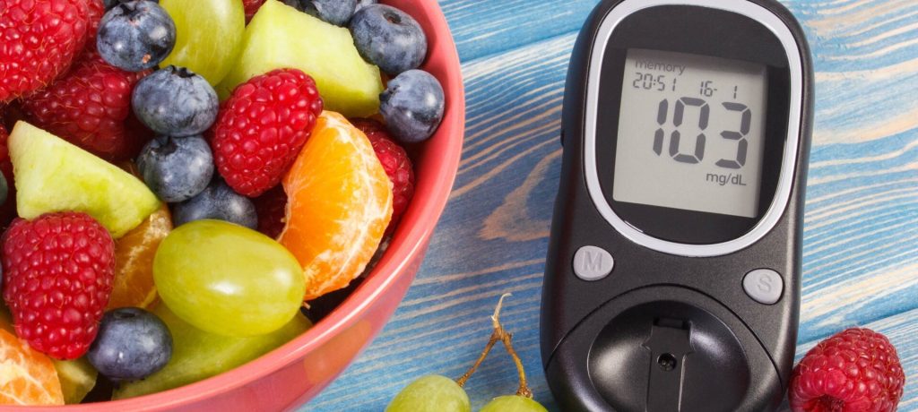 Fresh fruit salad and glucometer with result of measurement sugar level, concept of diabetes, diet, slimming, healthy lifestyles and nutrition