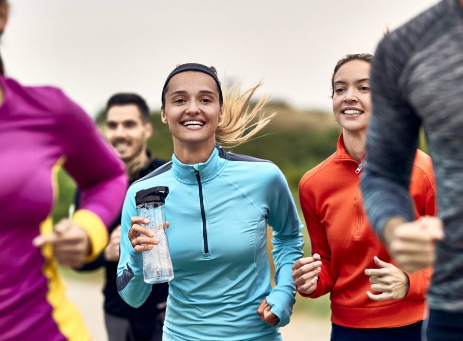 Young happy athletic women jogging with group of people in nature.