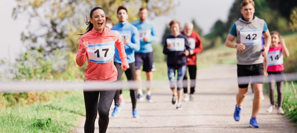 A large group of active multi generation people running a race competition in nature.