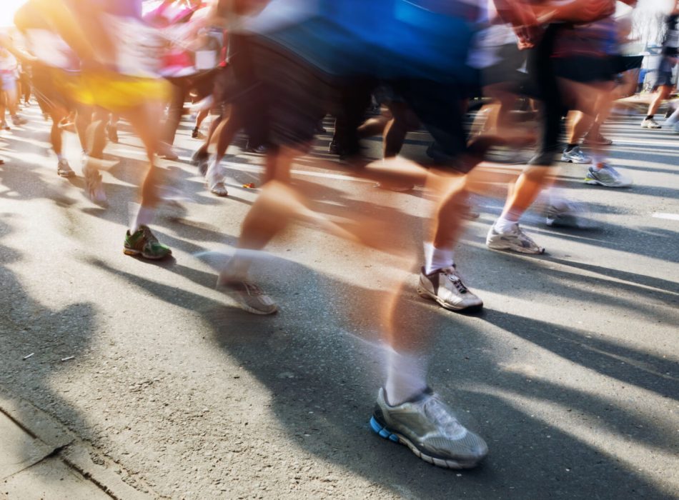 Marathon runners in motion. Running in the city, sun shining.