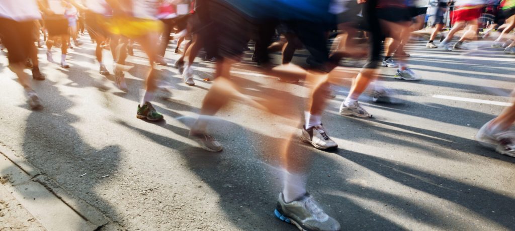 Marathon runners in motion. Running in the city, sun shining.