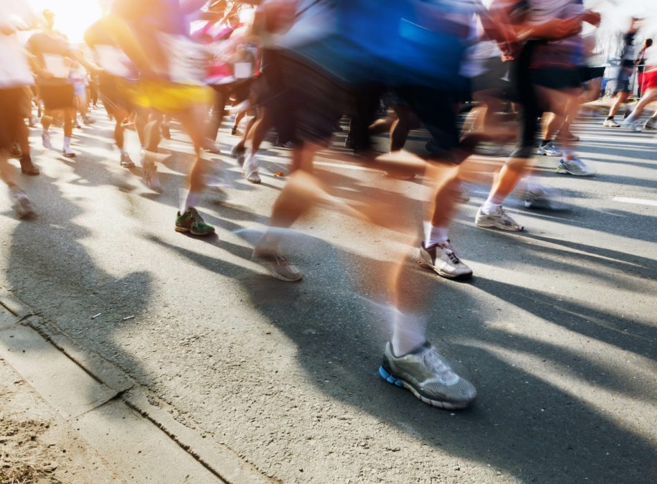 Marathon runners in motion. Running in the city, sun shining.