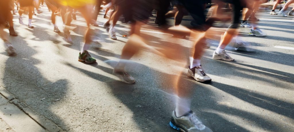 Marathon runners in motion. Running in the city, sun shining.