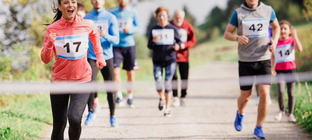 A large group of active multi generation people running a race competition in nature.