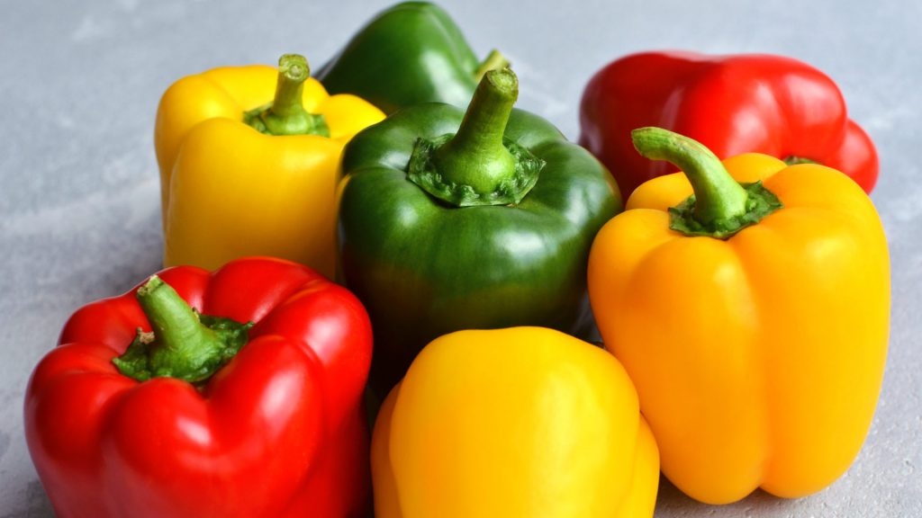 Green,,Red,And,Yellow,Bell,Pepper,On,Grey,Stone,Background.