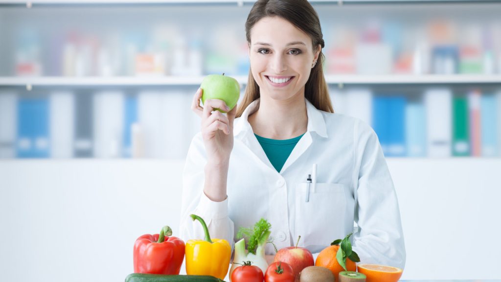 Smiling,Nutritionist,In,Her,Office,,She,Is,Holding,A,Green
