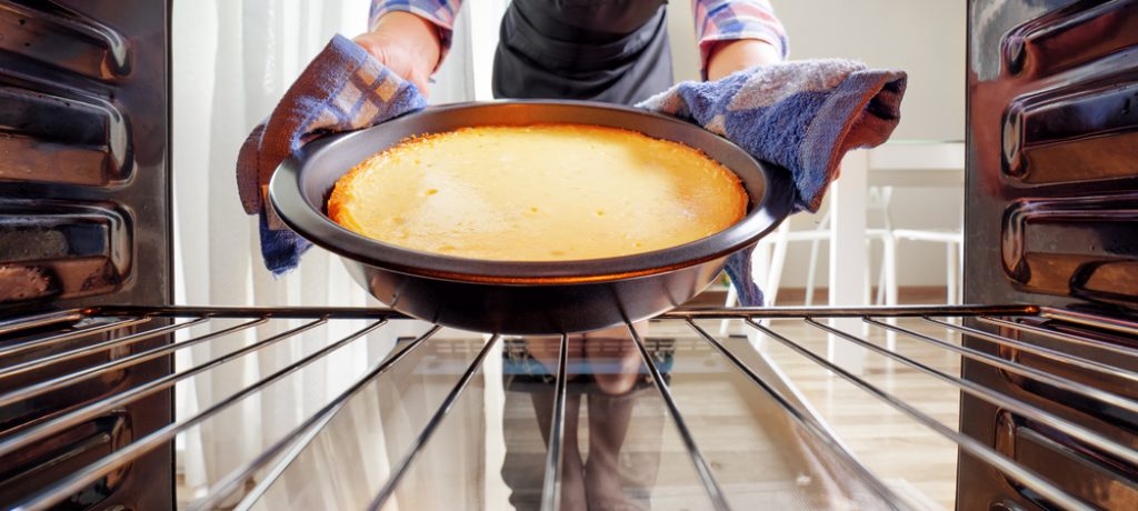Housewife,Using,Dishcloth,For,Taking,Cheesecake,Out,Of,Oven,In