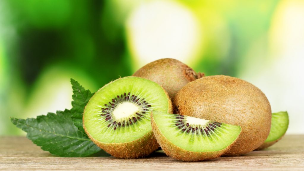 Juicy,Kiwi,Fruit,On,Wooden,Table,On,Green,Background