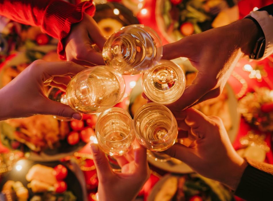 Top view of people toasting with champagne while enjoying Christmas Eve at the decorated holiday table