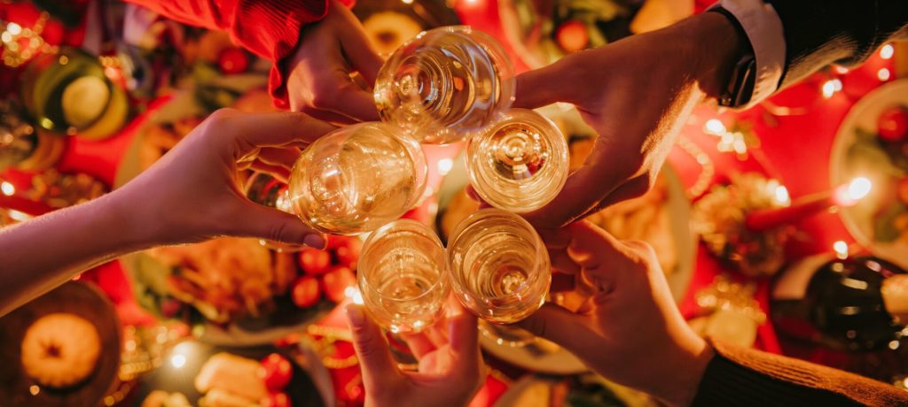 Top view of people toasting with champagne while enjoying Christmas Eve at the decorated holiday table