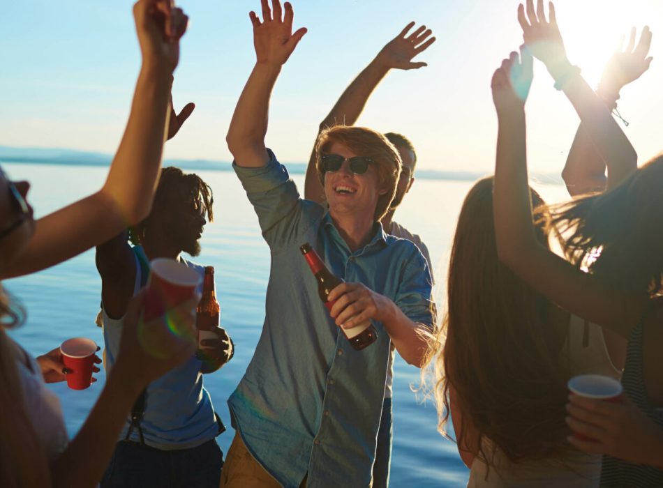 Dynamic guys and girls dancing with drinks on the beach