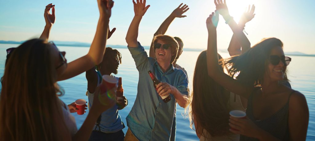 Dynamic guys and girls dancing with drinks on the beach